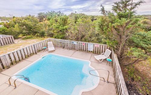 an outdoor swimming pool with two chairs at It's A Shore Thing - Nags Head MP 11.5, Ocean View, 130 Yds to Beach, Pool, Hot Tub, Rec Room in Nags Head