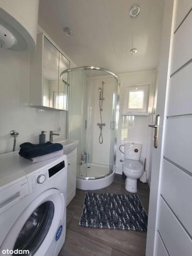 a bathroom with a shower toilet and a washing machine at Domki nad Szóstakiem in Orzechowo