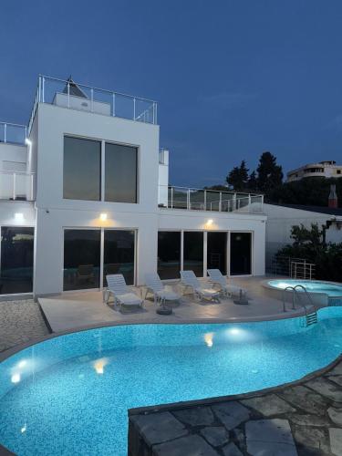 a villa with a swimming pool in front of a house at Sea Whisper Villa in Dobra Voda