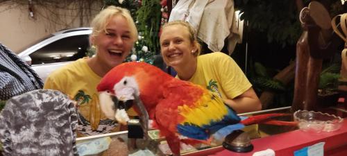 two women standing next to a parrot on a table at Hotel Caleta in San Miguel