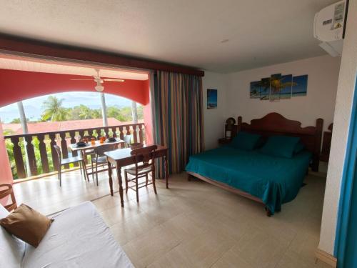 a bedroom with a bed and a balcony with a table at Hauts de Caritan in Sainte-Anne