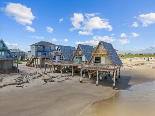 a row of houses on a beach in the sand at Sleep Over the Ocean in Surfside Beach