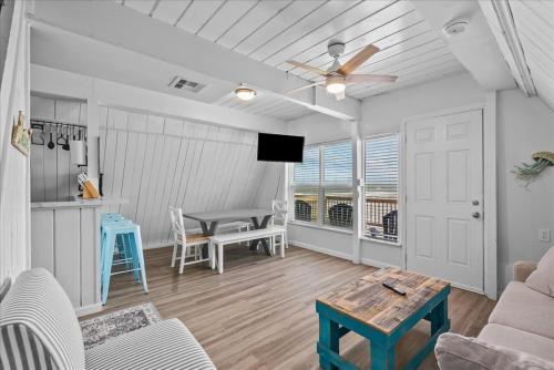 a living room with a ceiling fan and a table at Sleep Over the Ocean in Surfside Beach
