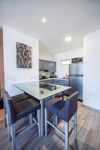 a kitchen with a glass table and chairs at Centro Cuauhtémoc Departamento en el Corazon de Monterrey in Monterrey