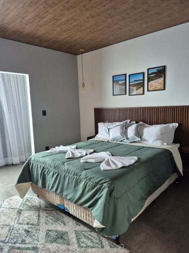 a bedroom with a large green bed with a wooden headboard at Mirante Vista Nobre in Maricá