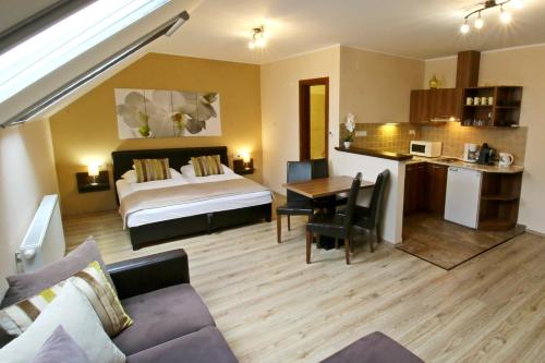 a hotel room with a bed and a table and a kitchen at Gellény Lux Apartman in Gyula