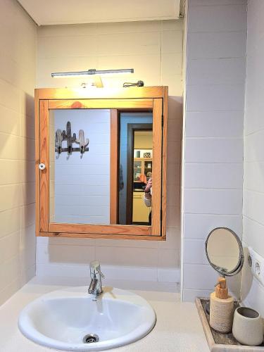 a bathroom with a sink and a mirror at Apartamento Can Rupit Playa Santandria con jardin y piscina in Son Carrio