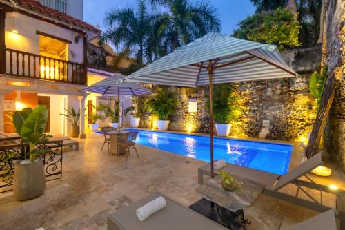 an outdoor patio with umbrellas and a swimming pool at El Marques Hotel Boutique By GEH Suites in Cartagena de Indias