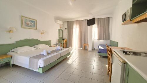 a bedroom with a large bed and a kitchen at Andromeda Hotel Apartments in Kos