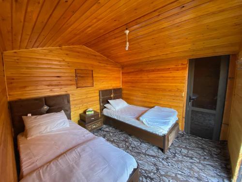 two beds in a room with wooden walls at Naif Bedouin tour in Wadi Rum