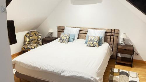a bedroom with a white bed with pillows and a chair at Gite la pause corrézienne in Troche