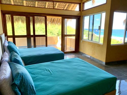 two beds in a room with a view of the ocean at Departamento con vista al mar, Wifi Starlink y AC en Playa San Agustinillo in San Agustinillo
