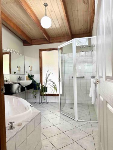 a bathroom with a shower and a tub and a sink at Halls Gap House in Halls Gap