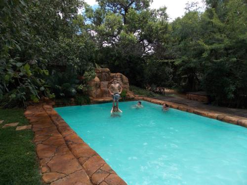 a boy jumping into a swimming pool in a backyard at Shangrila Innibos in Hartbeespoort