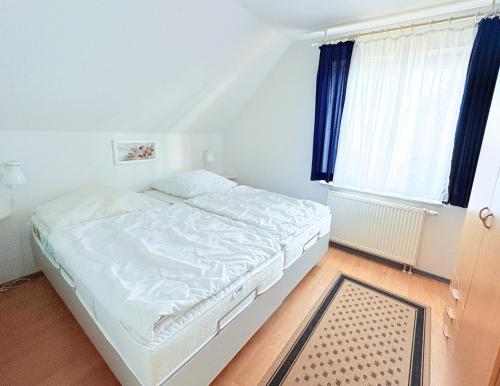 a white bed in a room with a window at Fewo Wellenherz - mit Balkon, 3 SZ, nah am Hafen in Breege