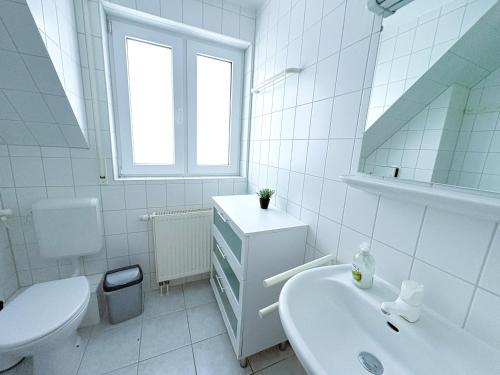 a white bathroom with a sink and a toilet at Fewo Wellenherz - mit Balkon, 3 SZ, nah am Hafen in Breege