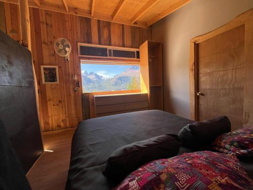 a bedroom with a bed and a window with mountains at Ventana al Castillo in Villa Cerro Castillo