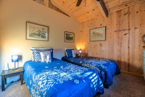 two beds in a room with wooden walls at Aunt Ginnys River View in Monte Rio