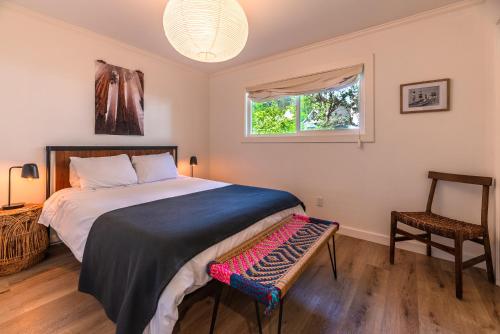 a bedroom with a bed and a window and a chair at Russian River Bungalow in Guerneville