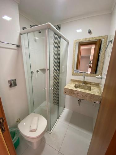 a bathroom with a shower and a toilet and a sink at Hotel Jardim do Mar in Torres