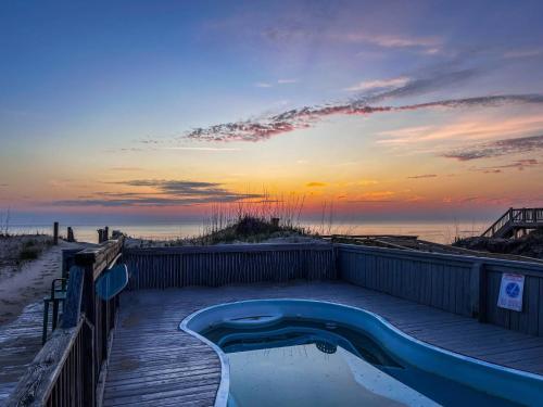 a hot tub on a wooden deck next to the beach at Sea Reunion - Nags Head MP 12.5, Oceanfront, Amazing Views! Pool, Hot Tub, Pets OK in Nags Head