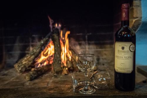 a bottle of wine and two glasses in front of a fireplace at Petroto in Fragkades