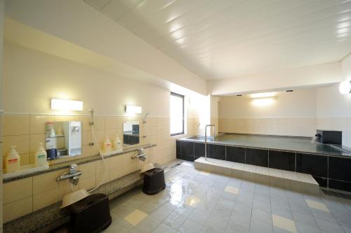 a large bathroom with a toilet and sinks and mirrors at Smile Hotel Yonezawa in Yonezawa