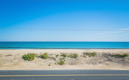 a road next to a beach with the ocean at The Tardis - Kitty Hawk MP 4.5, Ocean View, 275 Yds to Beach, Hot Tub, YR Flex Stays in Kitty Hawk