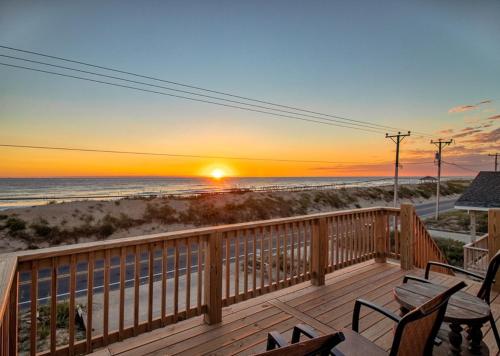 a deck with a view of the beach at sunset at The Tardis - Kitty Hawk MP 4.5, Ocean View, 275 Yds to Beach, Hot Tub, YR Flex Stays in Kitty Hawk