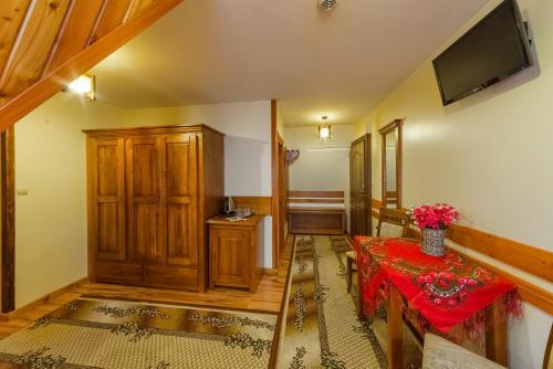 a living room with a table and a television at Willa Roztoka & SPA - idealne miejsce dla Twojej rodziny in Bukowina Tatrzańska