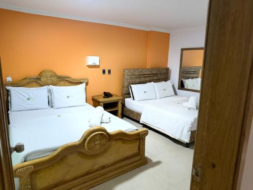 a hotel room with two beds and a mirror at Hotel Bosque Chapinero in Bogotá