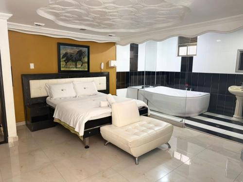a bedroom with a bed and a tub and a chair at Hotel Bosque Chapinero in Bogotá
