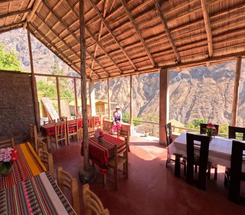 a room with tables and chairs with a mountain in the background at La Casa de Roy in Cosnihua