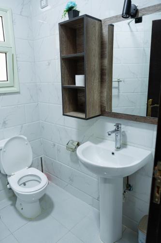 a white bathroom with a toilet and a sink at Juliana Beach Hurghada in Hurghada