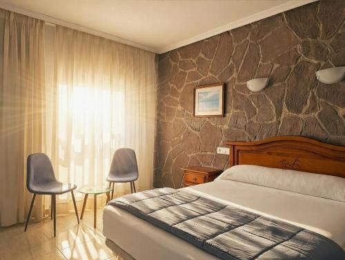 a bedroom with a bed and a stone wall at Hotel Mesón el 21 in Almería