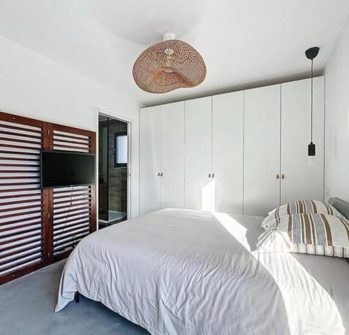 a bedroom with a large white bed and a television at La parenthèse basque in BIQ