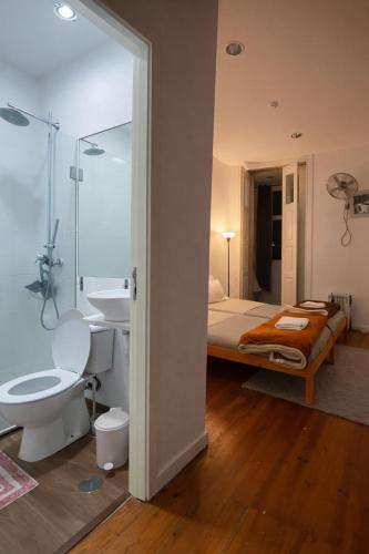 a bathroom with a bed and a sink and a toilet at Ndussole Guest House in Porto