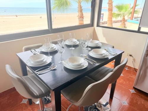 a dining table with chairs and plates and wine glasses at Las Gaviotas 2BR 2BA Ocean View 1st FL- 413 in Puerto Peñasco