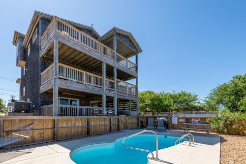 a house with a swimming pool and a deck at Carolina Cottage - Kitty Hawk, Oceanside, Walk to Beach, Pool, Hot Tub, Pool Table in Kitty Hawk