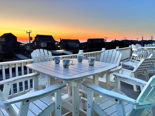 a table and chairs on a deck with the sunset at Jockey's Ridge Haven - NH MP 13, Pool-Open Now for 2026, Cabana, Hot Tub, Pets OK, YR Flex Stays in Nags Head