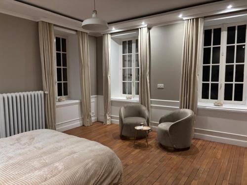 a bedroom with two chairs and a bed and windows at Chambre dans demeure de caractère in Missy-sur-Aisne