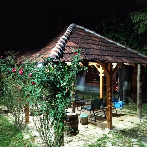 a wooden gazebo with a bench and roses at Veliki Banjan in Riznica Kraj