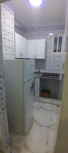 una cucina con mobili bianchi e un frigorifero di Appartement t2 a Luanda