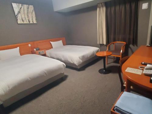 a hotel room with two beds and a desk at Hotel Route-Inn Saga Ekimae in Saga