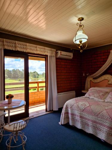 a bedroom with a bed and a table and a window at A Cabanha in Caçador