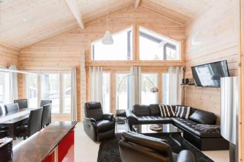 a living room with leather furniture and a flat screen tv at Villa Stella in Äkäslompolo