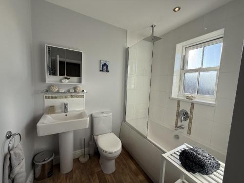 a white bathroom with a toilet and a sink at 12 Green Close at The Bay Filey, sleeps 8, 2 dogs welcome for free too in Filey