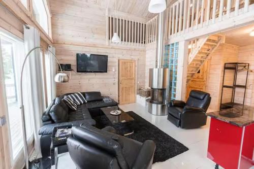 a living room with a black leather couch and a tv at Villa Stella in Äkäslompolo