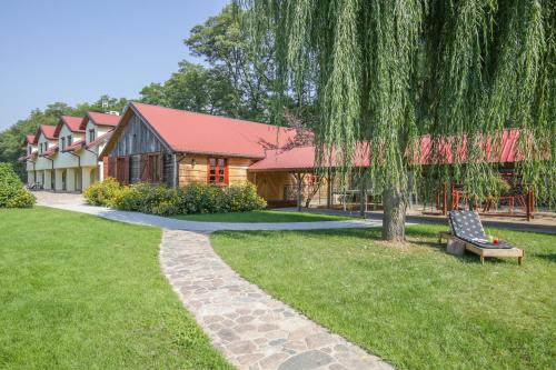 a building with a tree and a bench in a park at Gospoda Pazibroda in Maków Mazowiecki