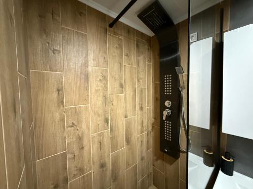 a bathroom with a shower with a wooden wall at Duplex Oasis Rooms in Ada